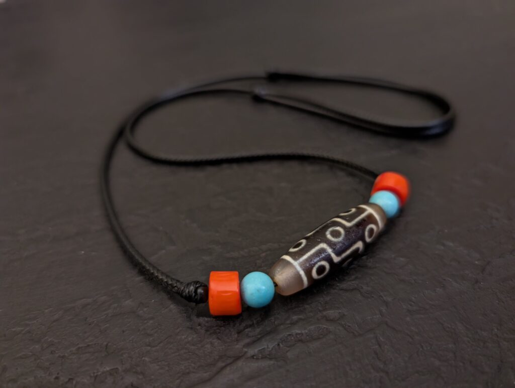 Dzi 9 occhi cosa significato nella tradizione tibetana, l'agata è decorata con magnesite e corallo, vista laterale