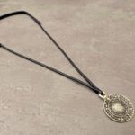 Bagua Spiegel Anhänger mit Ornament der acht Trigramme, Gesamtansicht mit Schnur auf neutralem Hintergrund